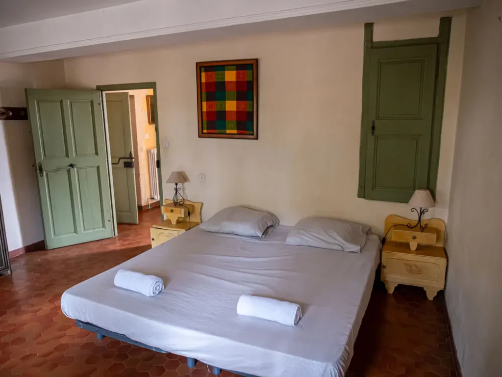 Chambre double d'un appartement du Domaine de la Baume, volets verts et tomettes